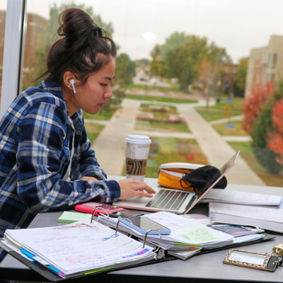 Student studying in front of windows overlooking campus from University View