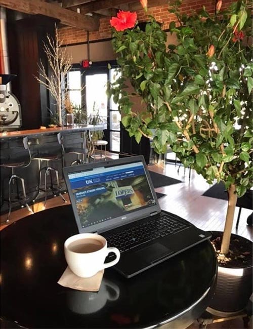 a picture of a laptop and a cup of coffee at a local coffee shop