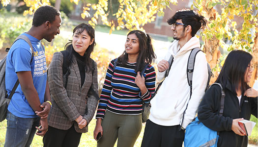 Group of 5 international students talking outside in the fall