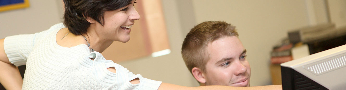 Staff helping student on computer