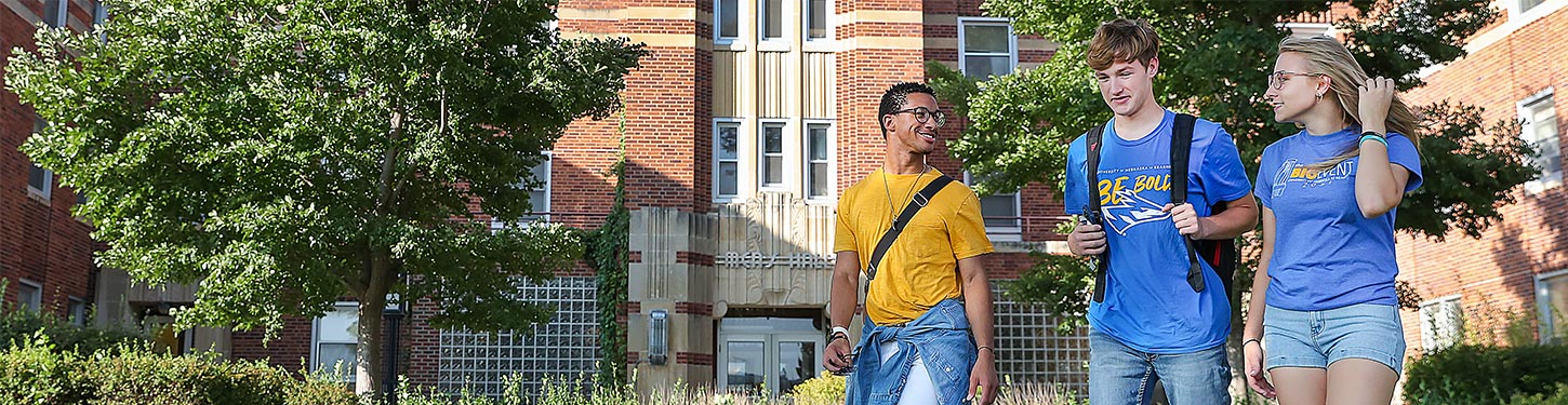 students walk across campus on a sunny afternoon