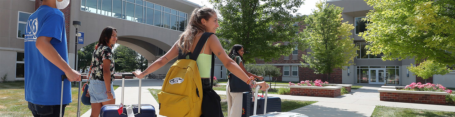 students carrying suitcases across campus