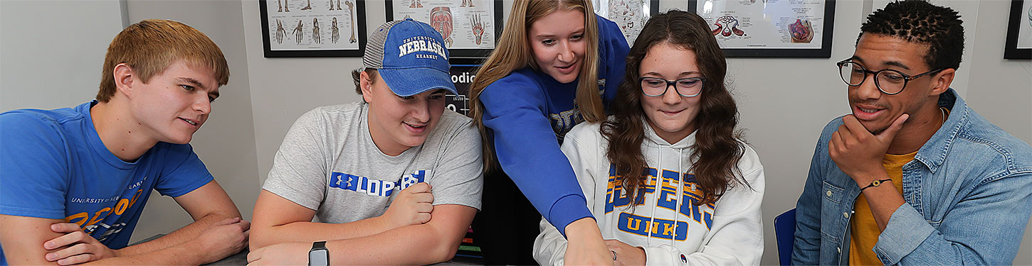 Students in a study group gather around a laptop