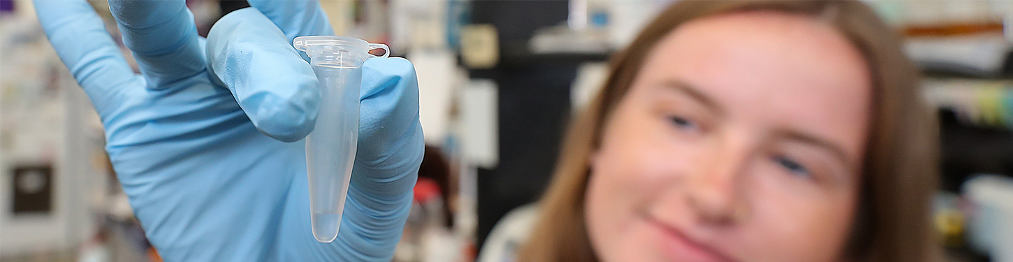 A student holds a vial in a gloved hand