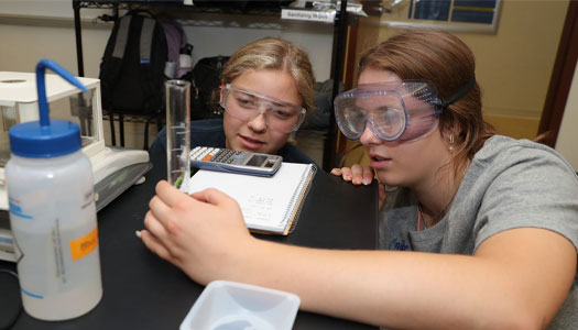 two students work on an experiment in a lab
