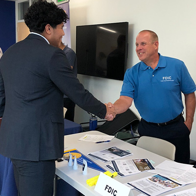 a student shakes hands with an employer at an event