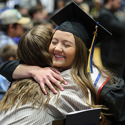 a student hugs someone a graduation