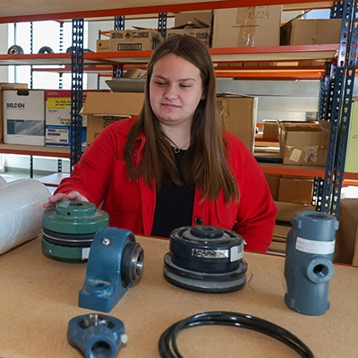 a supply Chain Management student examines equipment in a warehouse
