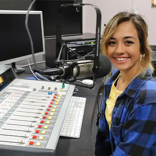 image of a student sitting in a radio broadcast booth