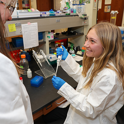 a student works with a professor in a lab