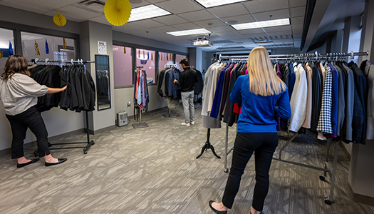 a student worker helps another student find professional attire