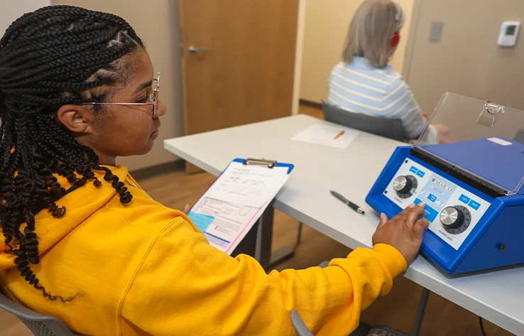 a student works with a patient during a hearing test