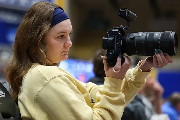 a student photographer works at a basketball game