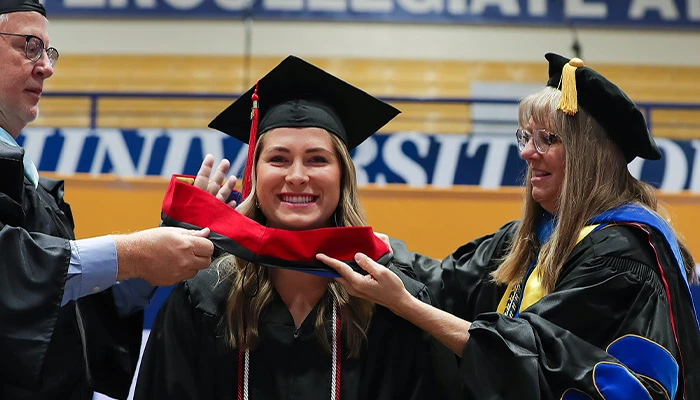 a student receives her hood at graduation