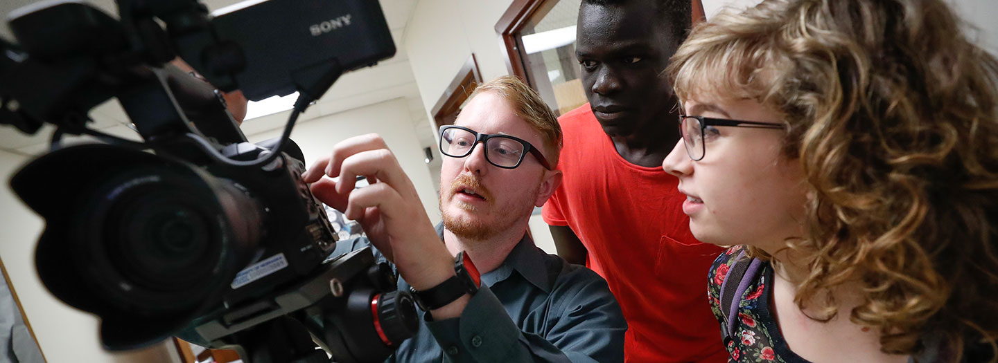 Student working with a video camera with a professor