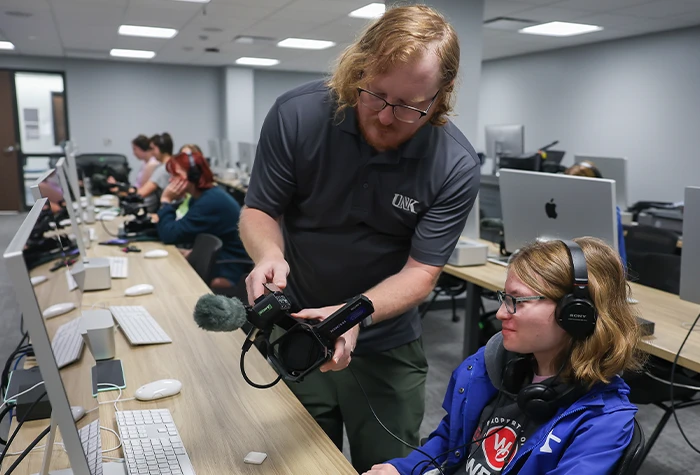 an instructor shows off camera equipment to a student