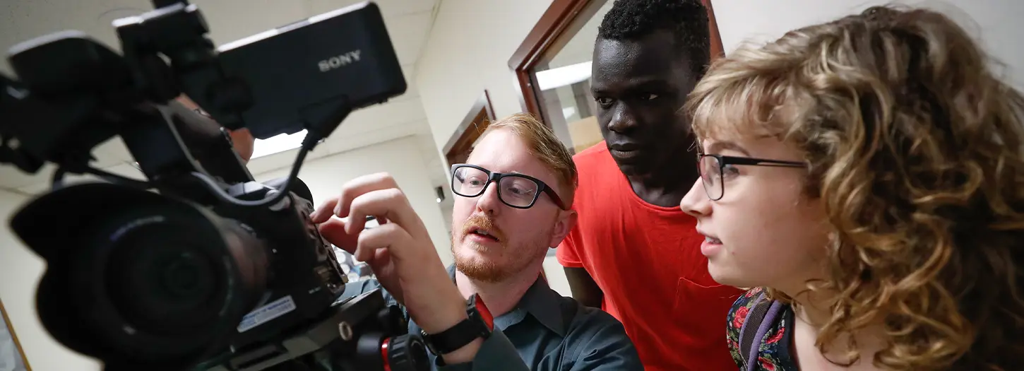 Student working with a video camera with a professor