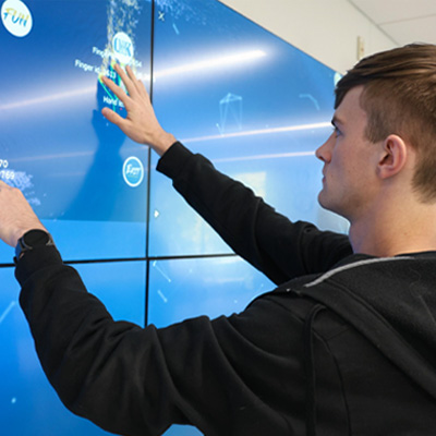 a student uses a giant touchscreen wall
