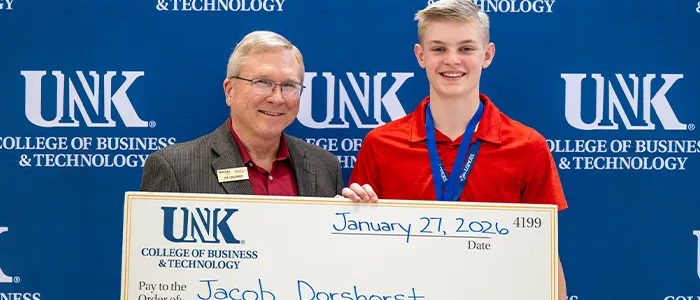 a student poses with a novelty check at discovery day