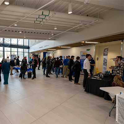 students and professionals walk booths at techfast