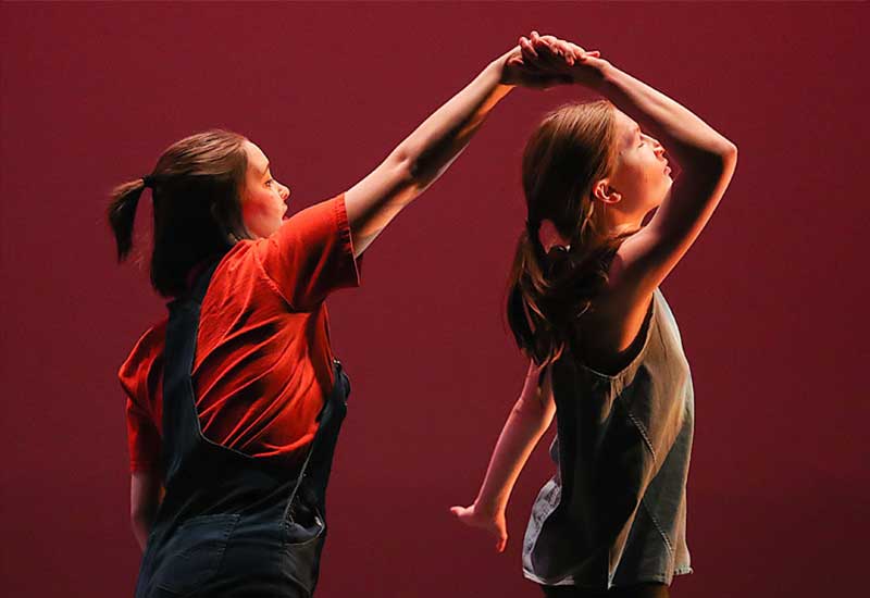 one student twirls another on stage during a dance recital