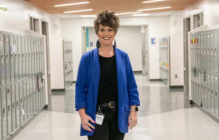 A unk graduate stands in the hallway of the school she serves as principal of