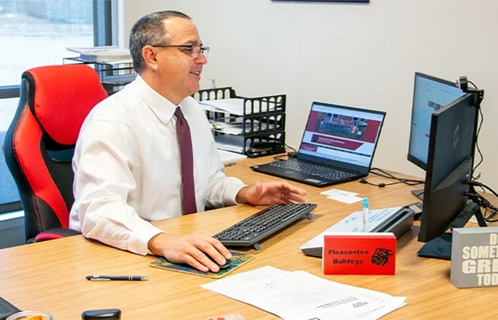 a superintendent sits at a desk, smiling as he works