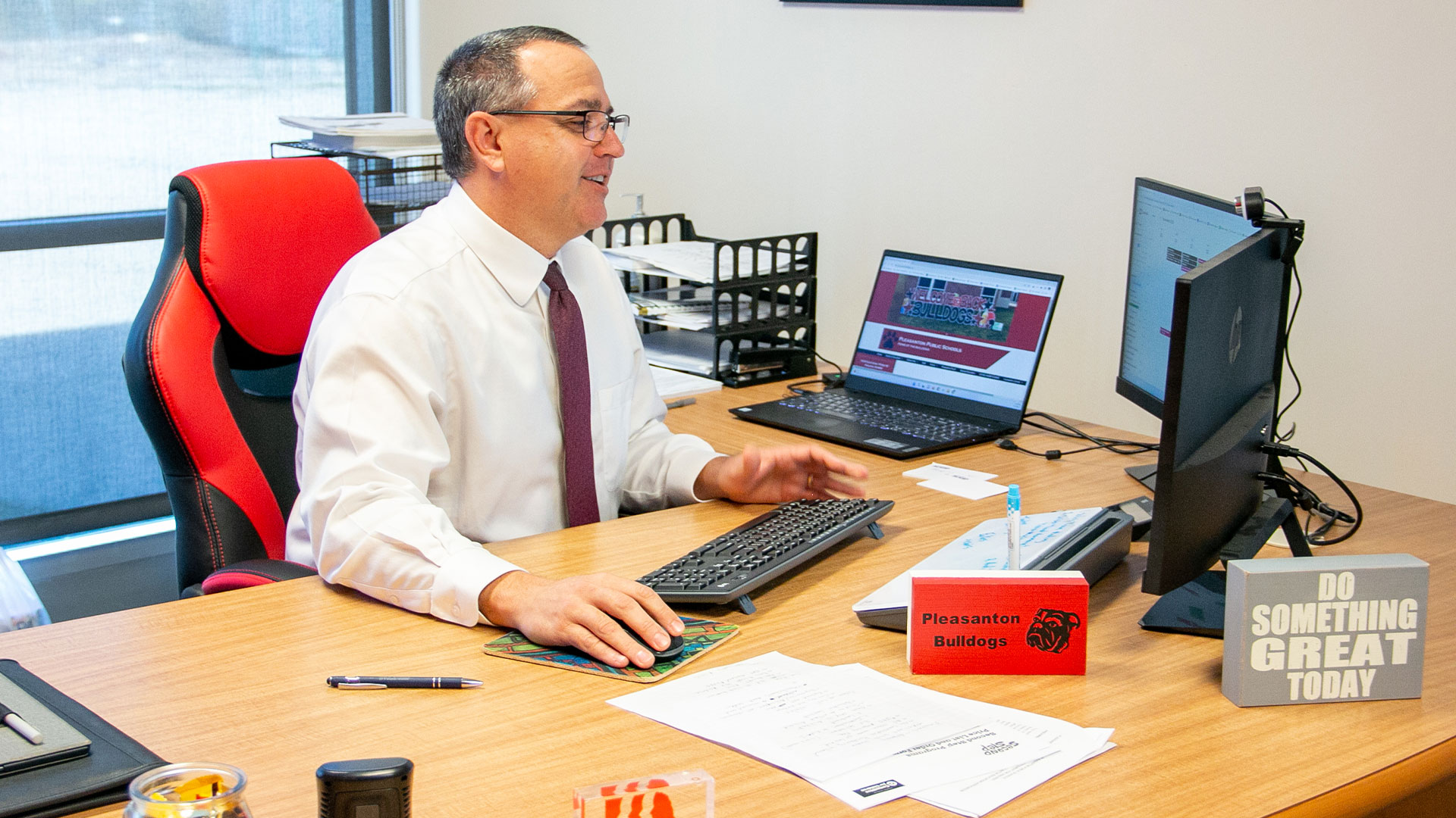 a superintendent sits at a desk, smiling as he works