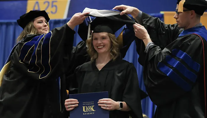 a graduate receives their hood during commencement