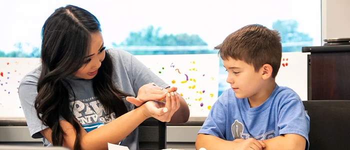 a speech pathology student works with a child in a classroom