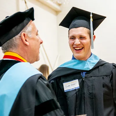 student and professor in academic robes at graduation