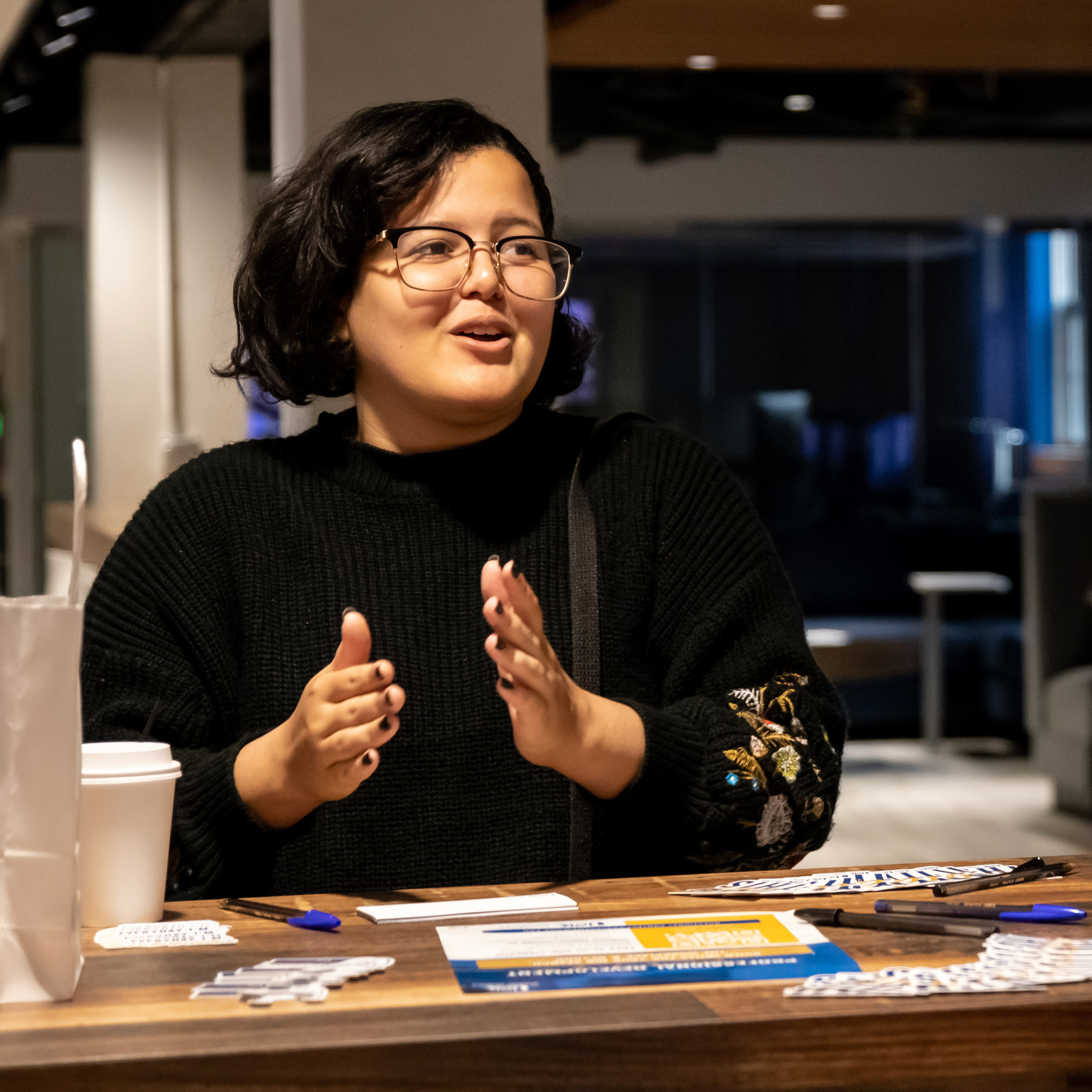 a student sits at a counter gesturing and speaking