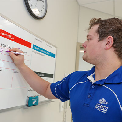 a student writes on a dry erase board