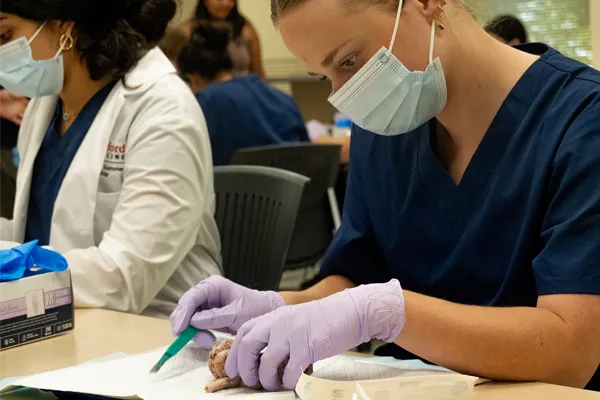 a masked student works during a clinical experience