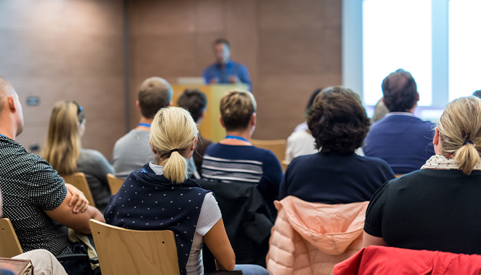 A speaker addresses a room full of people