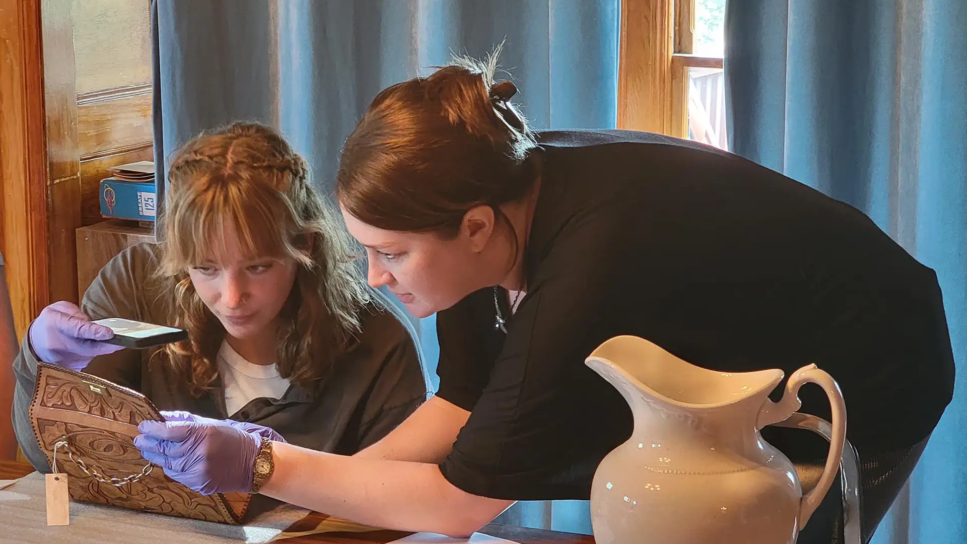 an instructor leans over to help a student with a museum exhibit