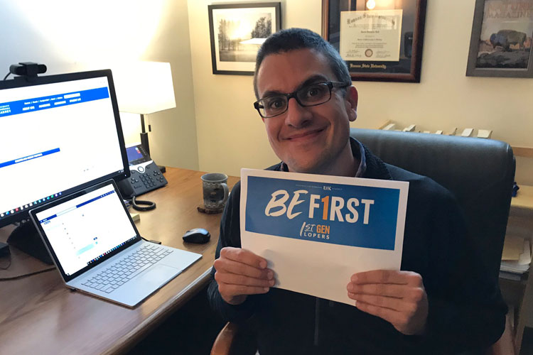 Dr. David Vail holds up a "Be first" sign supporting first generation students
