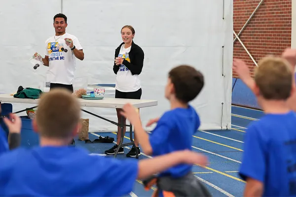 teachers talk to a group of students in a gym