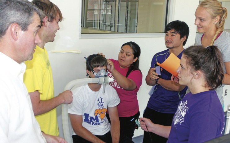 teacher and students affixing a breathing apparatus to an athlete