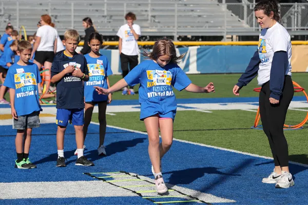 a teacher works with a student during a fitness day activity