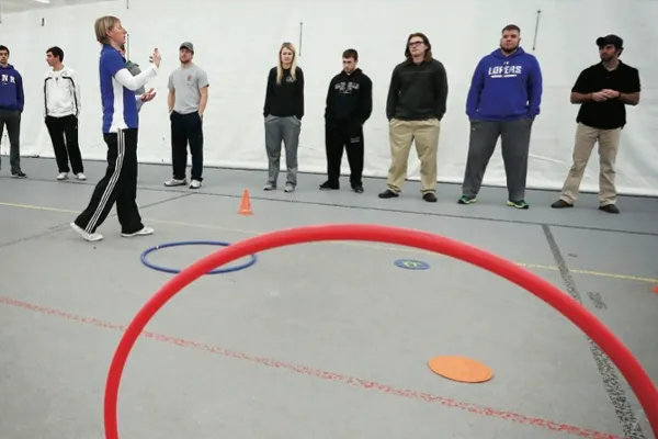 an instructor works with students in a gym
