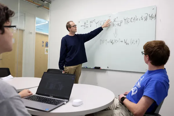 an instructor writes on a white board while student watch