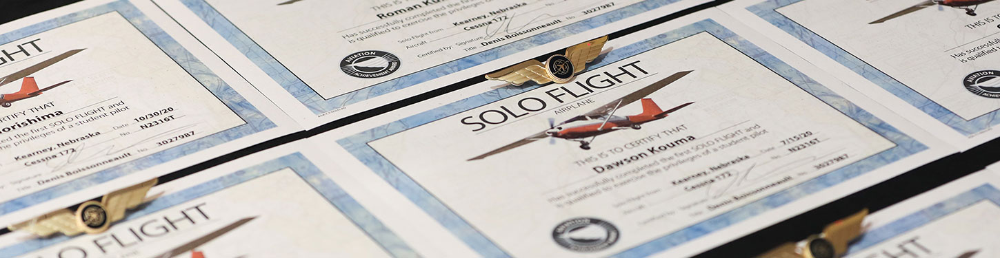 Solo Flight Certificates and wings sit on a table during a ceremony