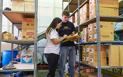Two students consult a clipboard in an industrial distribution lab