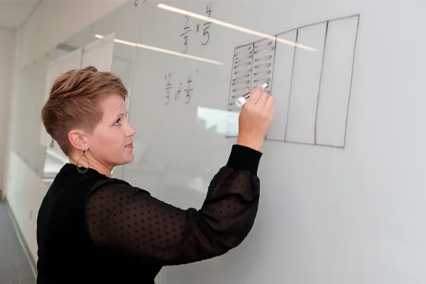 a teacher writes on a whiteboard