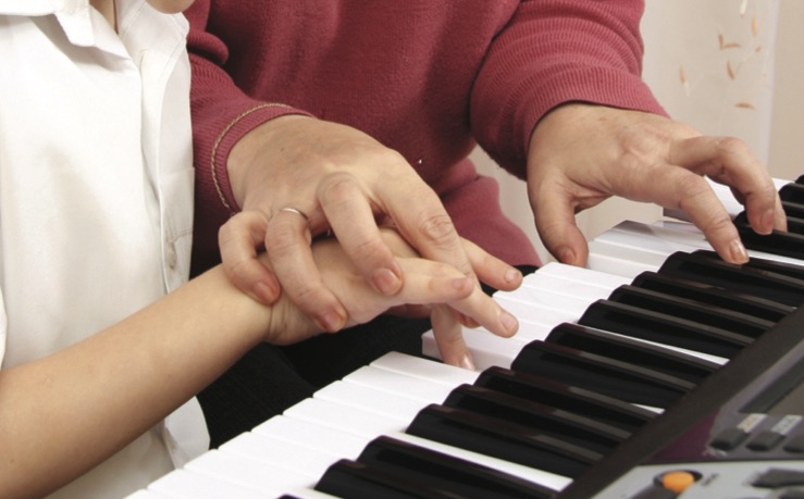 Women teaching youth to play piano