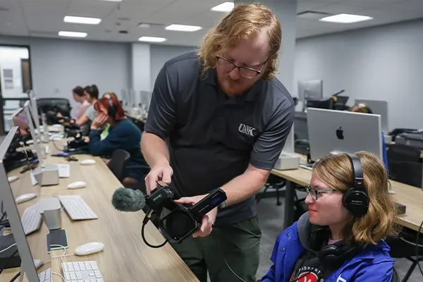 a professor showcases video equipment to a student