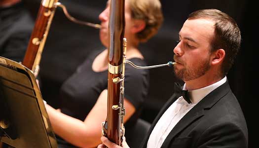 a man plays the bassoon in an orchestra