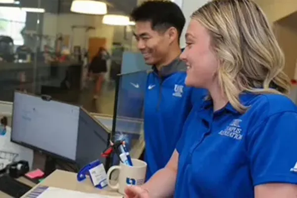 two people in blue polos stand at a welcome desk