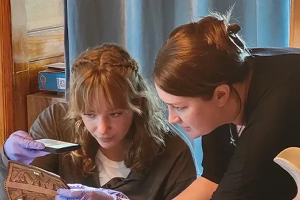 an instructor examines an artifact alongside a student